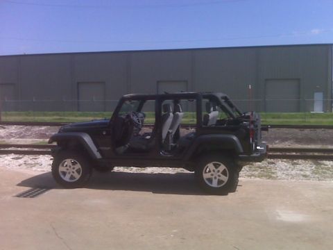 2008 Jeep Wrangler - A black Jeep Wrangler with its doors removed sits parked near railroad tracks.