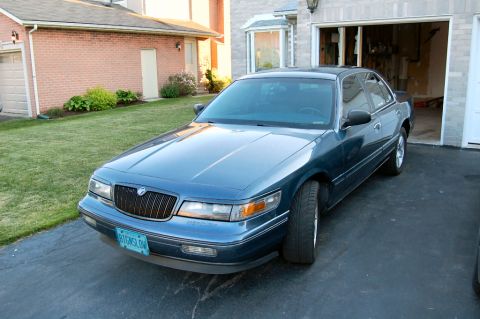 1985 Mercury Grand Marquis - This blue sedan, likely a 1995 Mercury Grand Marquis, is parked in a driveway. The license plate reads B1GHSL0W.