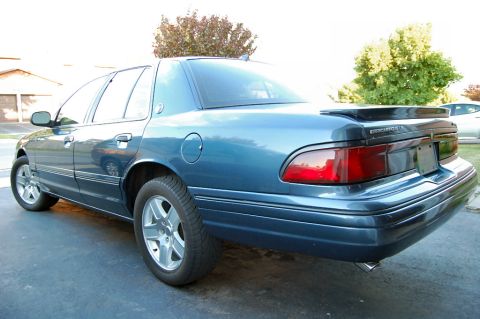 1985 Mercury Grand Marquis - This blue sedan has a spoiler and chrome accents, viewed from the rear three-quarter perspective.