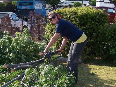 1991 Ford Bronco - Woman cuts tree branches with a Poulan chainsaw in a yard.
