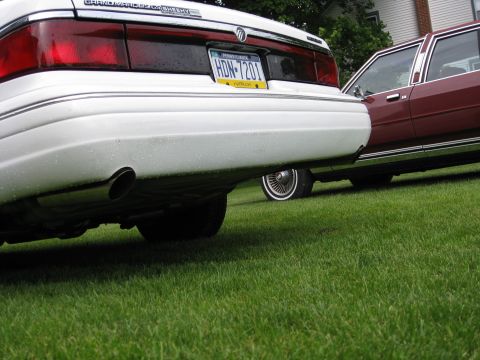 1996 Mercury Grand Marquis - The rear of a white Mercury Grand Marquis is shown, with a second vehicle partially visible to its right.