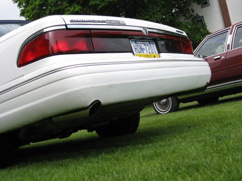 1996 Mercury Grand Marquis - The rear of a white 1996 Mercury Grand Marquis is visible next to a maroon car.