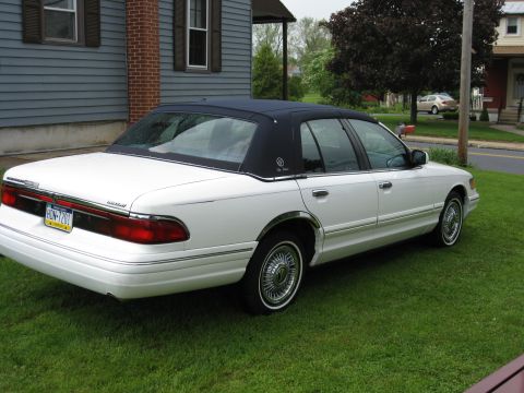 1996 Mercury Grand Marquis - This 1996 Mercury Grand Marquis features a white exterior with a contrasting dark blue vinyl roof and is shown from the rear 3/4 angle.