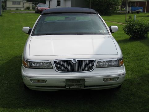 1996 Mercury Grand Marquis - A white Mercury Grand Marquis convertible is parked on a grassy lawn with a red car in the background.