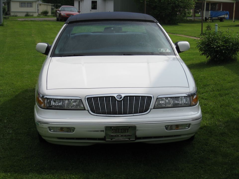 White Mercury Grand Marquis convertible parked on grass, black top up. License plate reads SHEEHY