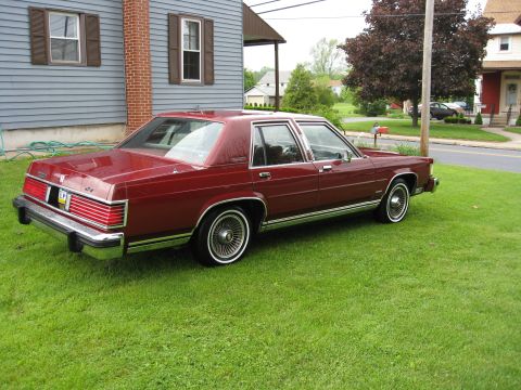 1984 Mercury Grand Marquis - A maroon sedan sits on a green lawn in front of a house.