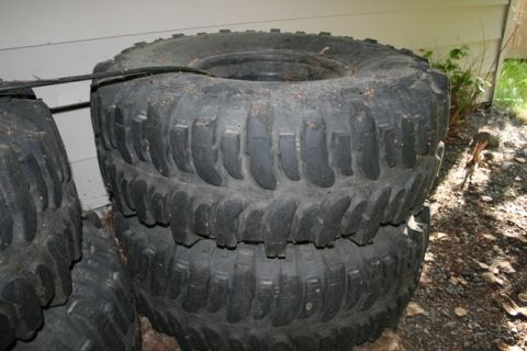 1990 Chevrolet Suburban - A collection of off-road tires are stacked outdoors, showing their aggressive tread patterns.