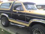 1986 Ford Bronco - A two-tone Ford Bronco is parked outdoors, showing its side profile and front quarter.