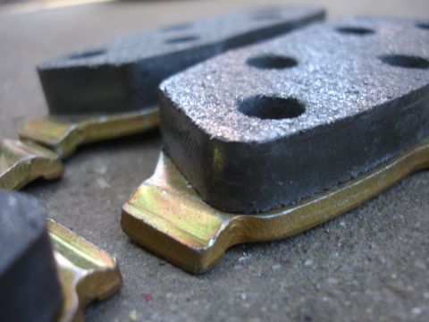 1990 Ford Taurus - Several brake pads are shown, some with metal backing plates, resting on a concrete surface.