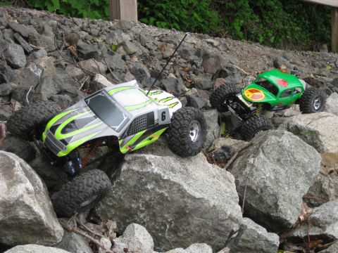 2010 Ford Pickup - Two remote control rock crawlers, one resembling a green beetle and the other a grey pickup truck, traverse a challenging rocky landscape.
