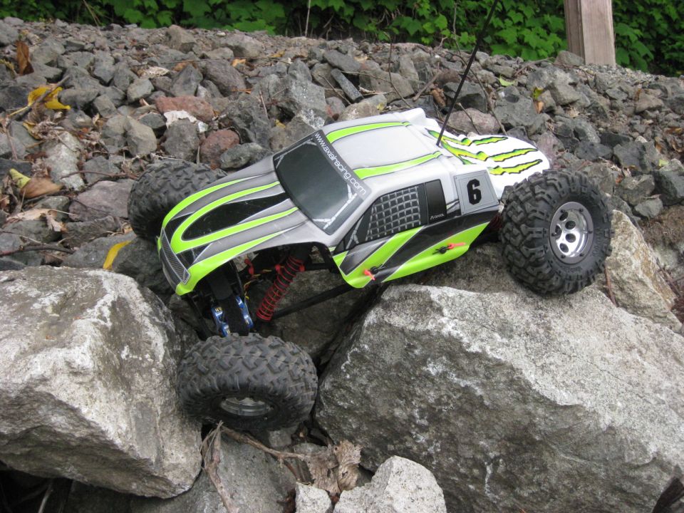 RC rock crawler with green and black graphics on rocks. Number 6 on side
