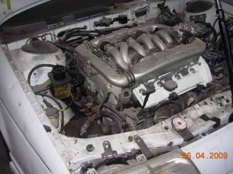 1995 Ford Taurus - The engine bay of a white vehicle is shown, a V6 engine with prominent intake runners.