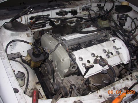 1995 Ford Taurus - Close-up view of a vehicle's engine bay, white valve covers and various engine components.
