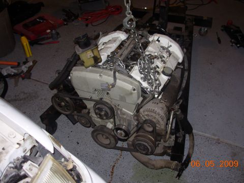 1995 Ford Taurus - Engine removed from a vehicle, suspended by chains in a workshop setting.