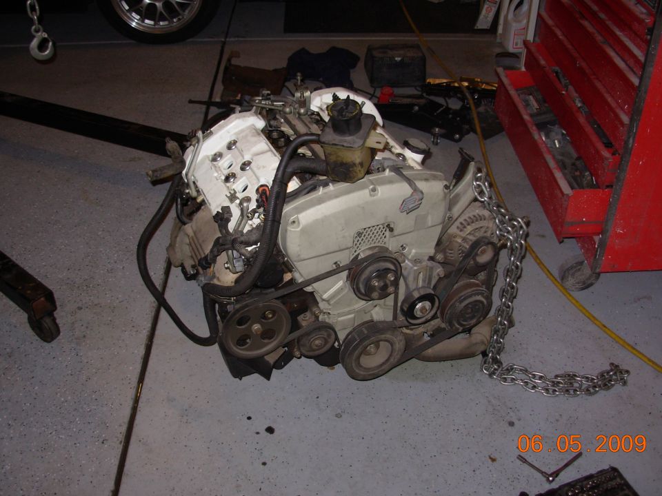 Engine assembly with chains attached, next to a red toolbox