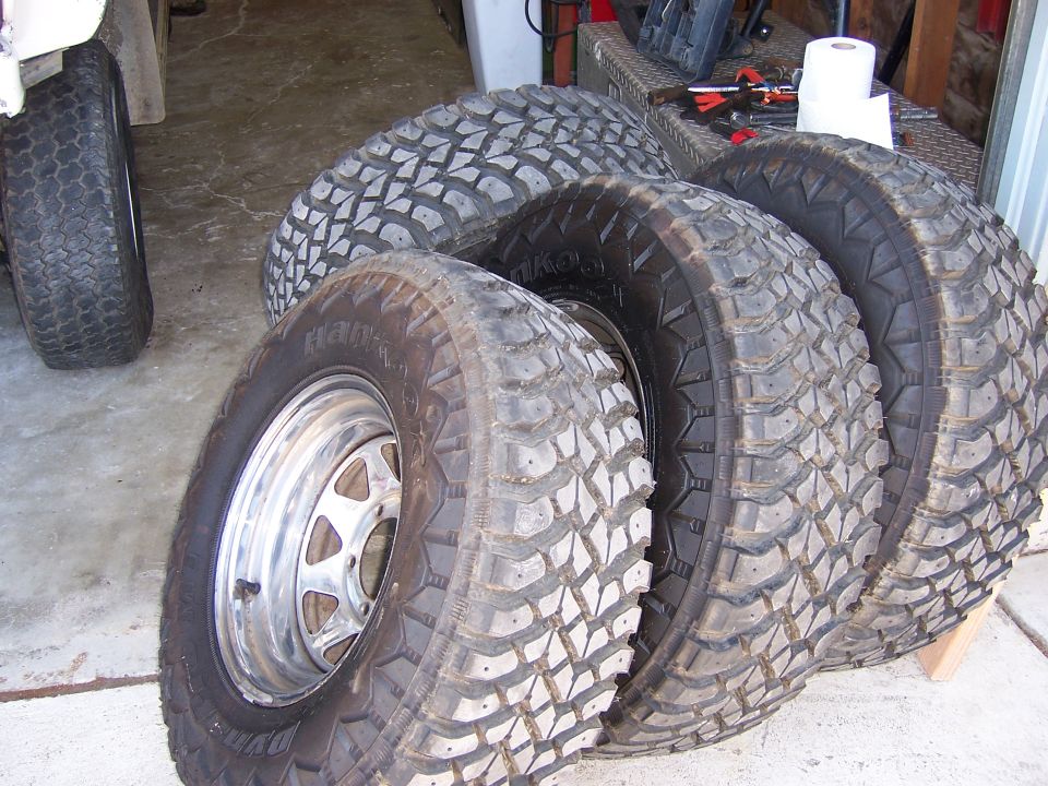 Four off-road tires and one chrome wheel