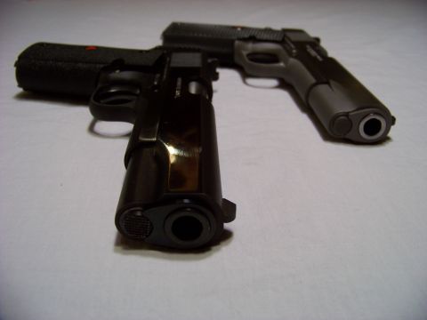 1995 Mercury Grand Marquis - Two handguns are displayed on a white surface, with one in the foreground and another slightly behind it.