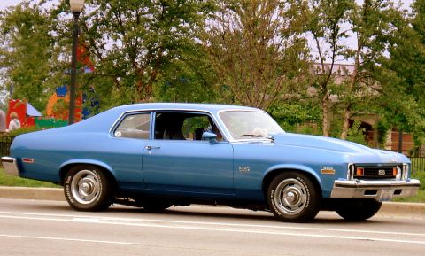 1998 Ford Taurus - This blue 1973 Chevrolet Nova SS coupe is seen from the side, its distinctive SS badging and hood.