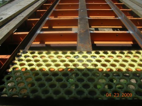 1991 Ford F-150 - The deck of a gooseneck trailer is visible, yellow perforated metal and orange structural beams.