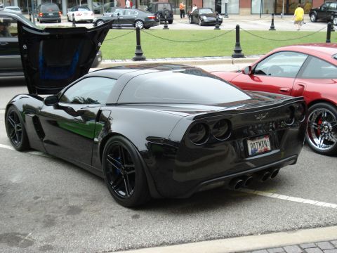 1998 Ford Taurus - A black Chevrolet Corvette Z06 is parked with its hood open, next to a red sports car.