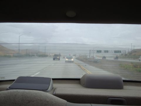 1990 Ford Taurus - Looking out from the back seat of a car at a highway scene with multiple vehicles driving in the rain.