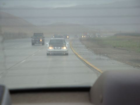 1990 Ford Taurus - Driving on a wet highway in foggy conditions with multiple vehicles ahead.