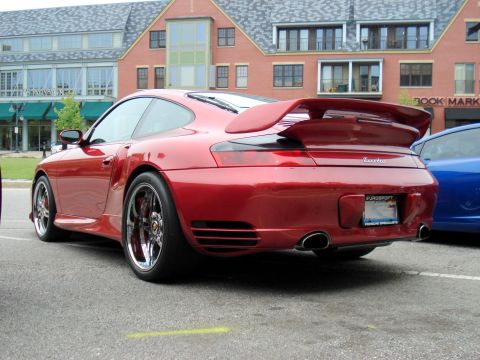 1998 Ford Taurus - A red Porsche 911 Turbo is parked next to a blue car, with a building in the background.