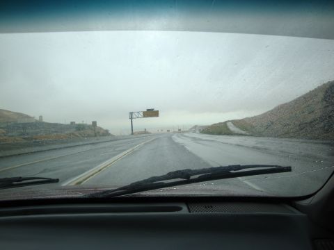 1990 Ford Taurus - Driving on a wet highway under an overcast sky, with a road sign visible in the distance.