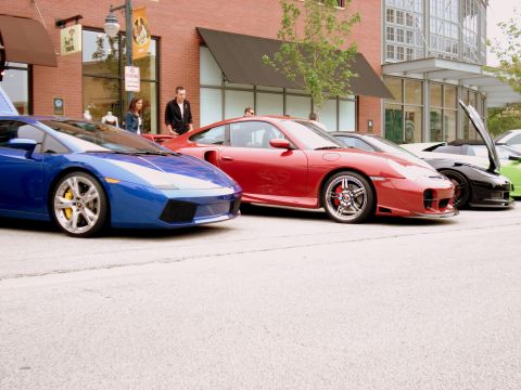 1998 Ford Taurus - Several exotic sports cars are parked in a row on a street during a Cars and Coffee event.