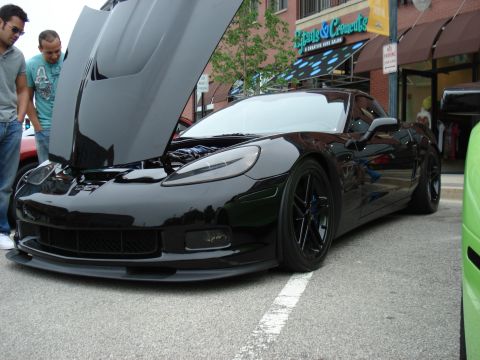 1998 Ford Taurus - A black Chevrolet Corvette C6 is parked on a street with its hood open, revealing the engine bay.