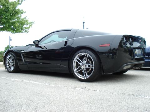 1998 Ford Taurus - A black sports car is parked on asphalt, viewed from the side with chrome wheels.