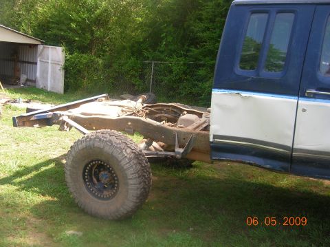 1991 Ford F-150 - The rear section of a truck cab is shown attached to its chassis, with a large off-road tire mounted.