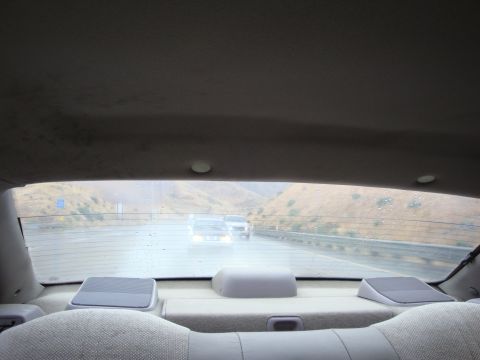 1990 Ford Taurus - Driving on a wet highway with other vehicles in view, seen from the back seat.