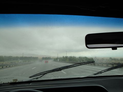 1990 Ford Taurus - Driving on a wet highway with rain falling, a distant vehicle is visible ahead.