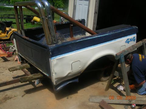 1991 Ford F-150 - This 1991 Ford F-150 pickup bed features a custom roll cage and dual exhaust pipes, with a visible 4x4 decal.