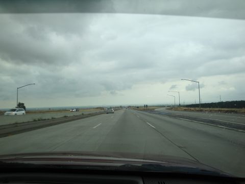 1990 Ford Taurus - View from a car driving on a highway with several vehicles ahead and to the side under an overcast sky.
