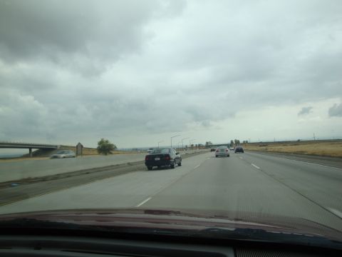 1990 Ford Taurus - Multiple vehicles travel along a highway on an overcast day.