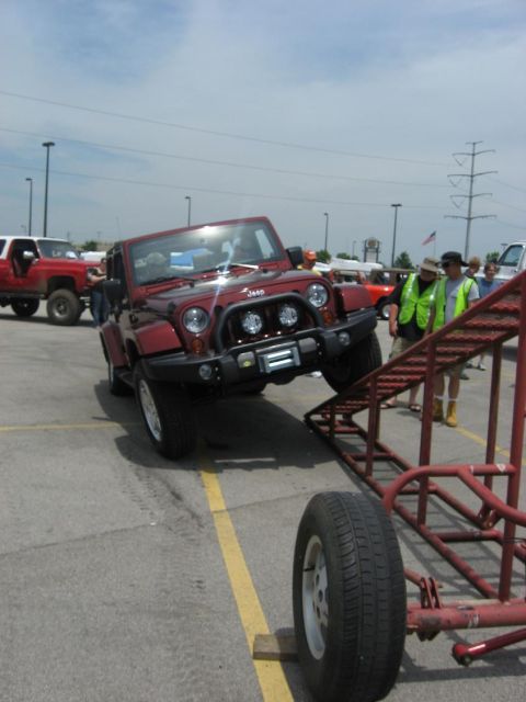 1987 Suzuki Samurai - A red Jeep Wrangler is positioned on a metal ramp during an off-roading event.