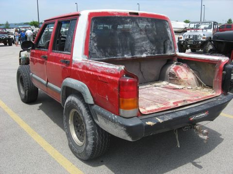 1987 Suzuki Samurai - This red Jeep Cherokee has been converted into a pickup truck, with a modified rear bed and a white camper shell top.