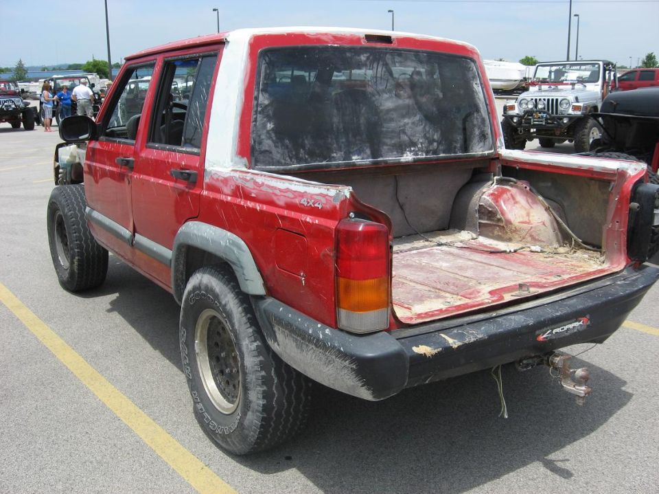 Red Jeep Cherokee sport utility vehicle modified into a pickup truck, rear view
