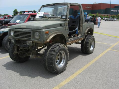 1987 Suzuki Samurai - A heavily modified 1987 Suzuki Samurai is parked in a lot next to other vehicles.