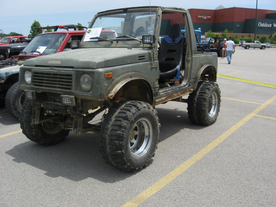 Modified 1987 Suzuki Samurai with large tires and lifted suspension parked in a lot