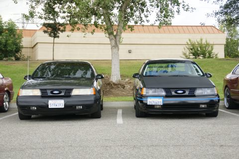 1990 Ford Taurus - Two 1990 Ford Taurus sedans are parked next to each other in a lot.