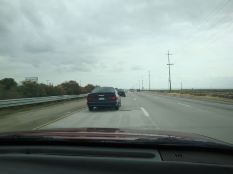 1990 Ford Taurus - A 1990 Ford Taurus is seen driving on a highway under a cloudy sky.