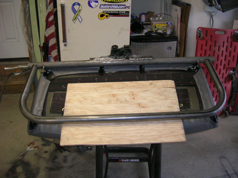 Roll cage tubing over wooden planks on a workbench