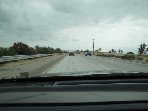 1990 Ford Taurus - Two cars are visible on a highway under a cloudy sky.
