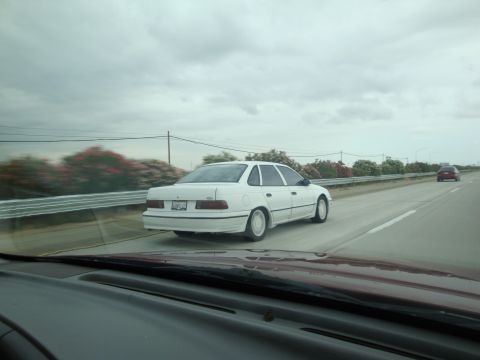 1990 Ford Taurus - White 1990 Ford Taurus seen from another vehicle on the highway.