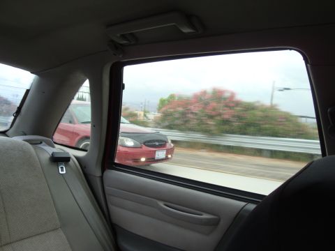 1990 Ford Taurus - View of a red 1990 Ford Taurus from the interior of another vehicle as it travels on a highway.