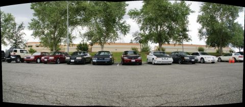 1990 Ford Taurus - A row of vehicles are parked in a lot, with several Ford Crown Victorias visible among them.