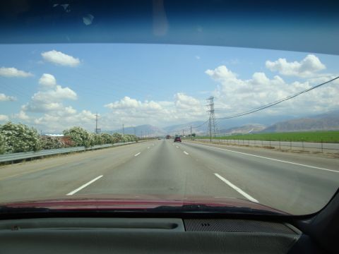 1990 Ford Taurus - A view from inside a vehicle shows a highway stretching towards distant mountains under a partly cloudy sky.